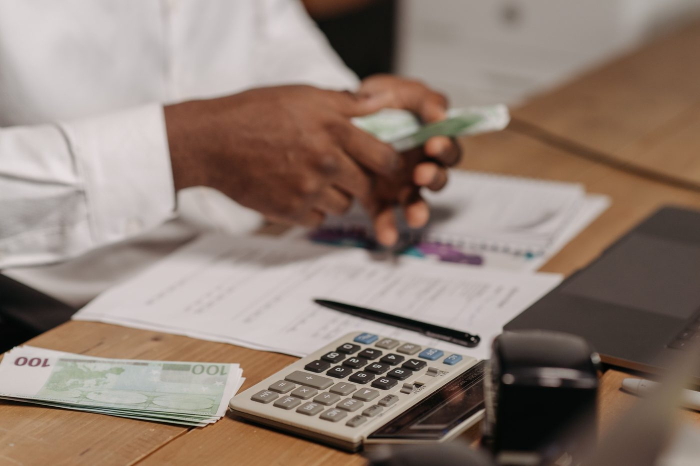 Hands counting banknotes next to a calculator and documents