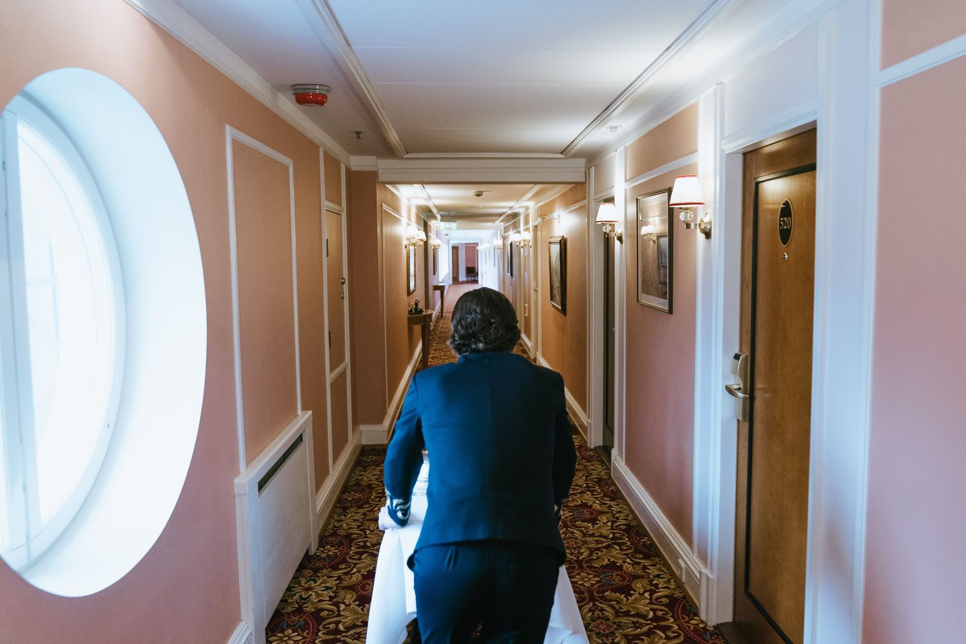 Staff member pushing a cart down a hotel corridor